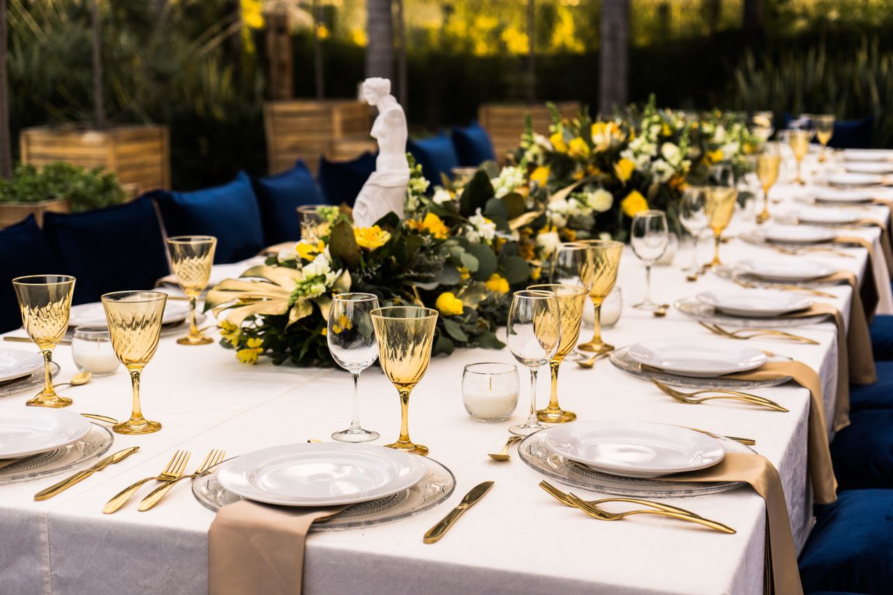 Beautifully arranged outdoor table setting with elegant flatware and yellow floral centerpiece for a special event.